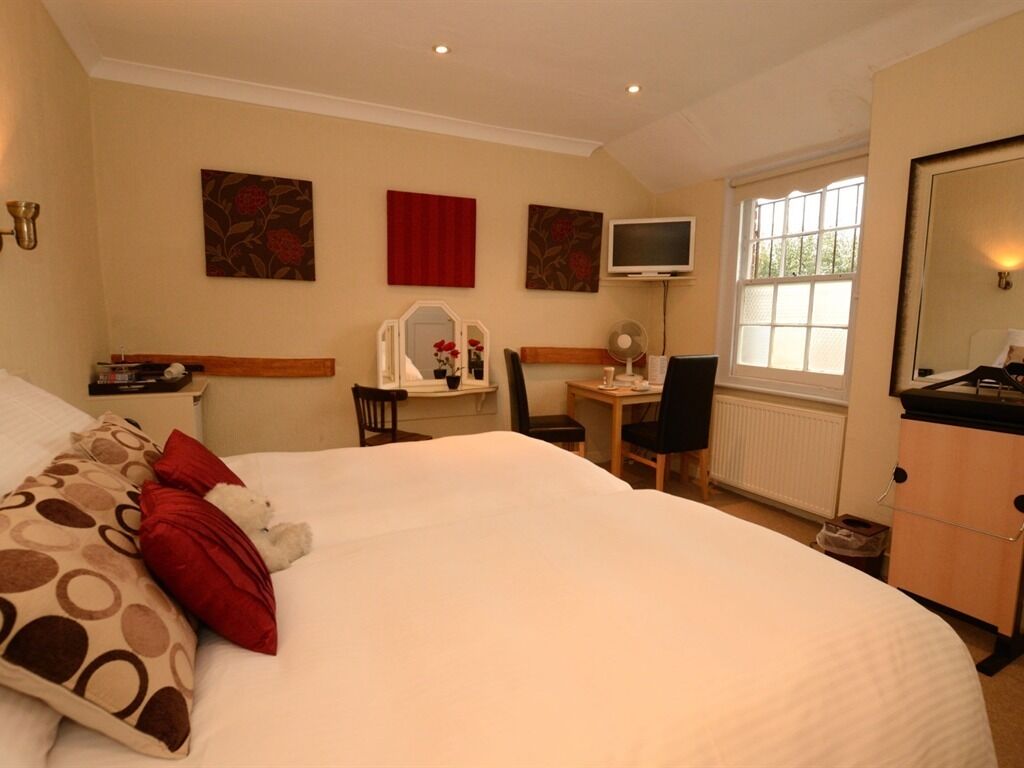 A hotel room with a large bed, a desk with a chair, a television, and a window with a view.
