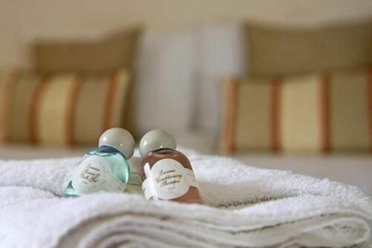 Ein ordentlich bezogenes Bett mit einem weißen Handtuch und drei Lotionflaschen darauf.