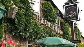 A building with a sign reading "The Greyhound Inn" and a pub sign above it. - The Greyhound Inn Aldbury (Tring)