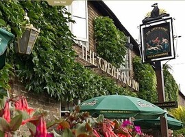 Un edificio con un letrero que dice "The Greyhound Inn" y un cartel de pub encima.