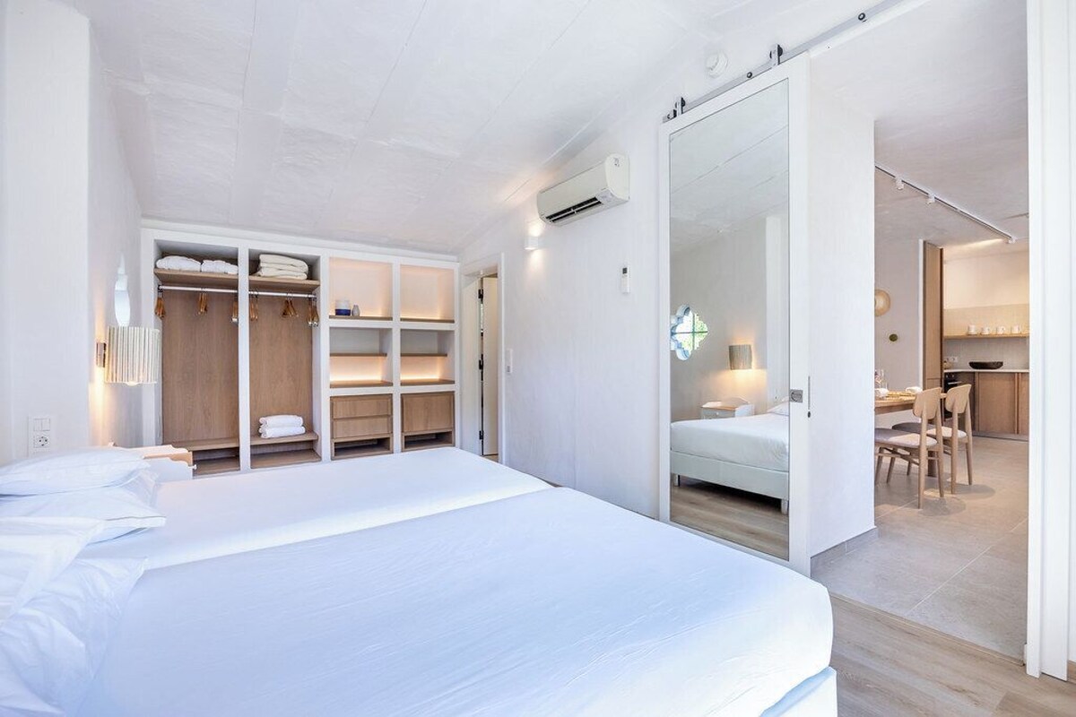 Ein modernes Schlafzimmer mit einem großen Bett, einem eingebauten Kleiderschrank und einer Schiebetür zu einem Essbereich.