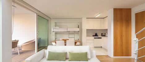 A modern interior with a white sofa, a dining area, and a kitchen.