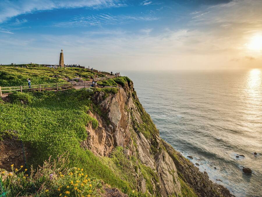 Un paisaje costero con un faro, acantilados cubiertos de hierba y vistas al mar.