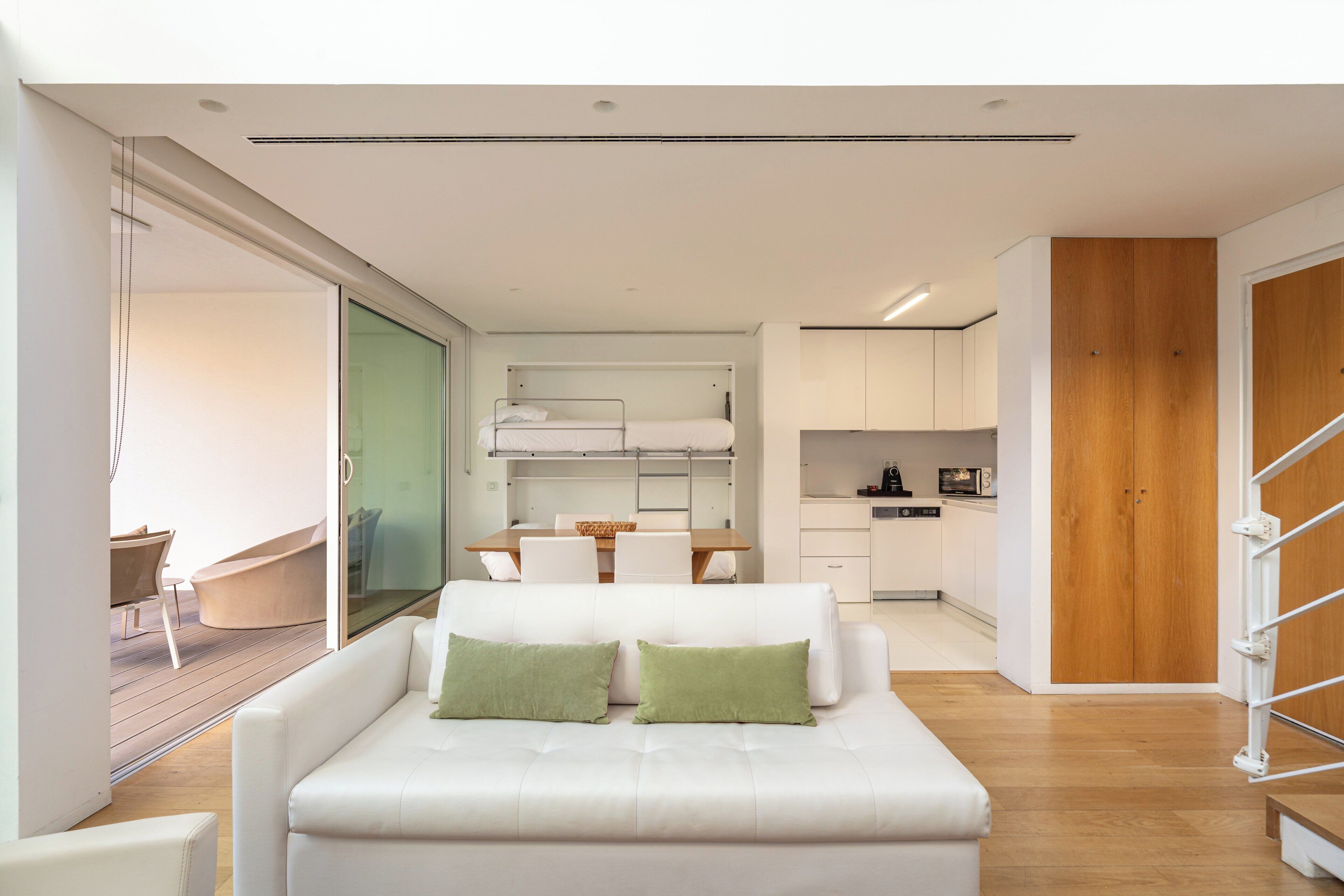 A modern interior with a sofa, a dining area, and a kitchen.