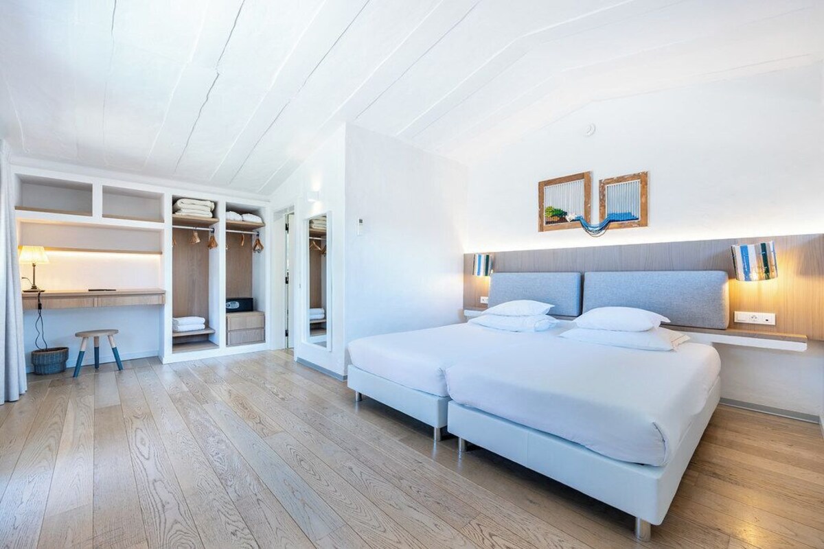 Ein Schlafzimmer mit einem großen Bett, einem Nachttisch, einem Kleiderschrank und einem Schreibtisch mit Stuhl.