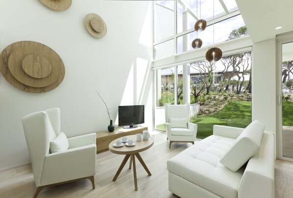Relax in this spacious living room with a clear view of the outdoors, featuring a comfortable seating area and a flat-screen television.