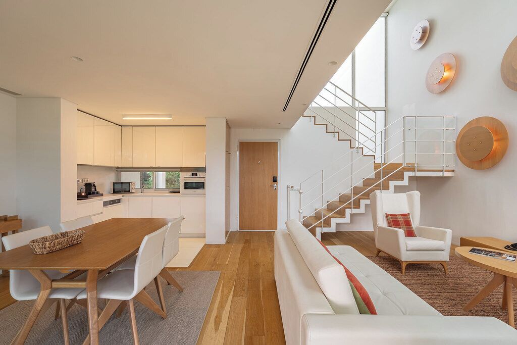 A modern interior with a dining area, kitchen, staircase, and seating.