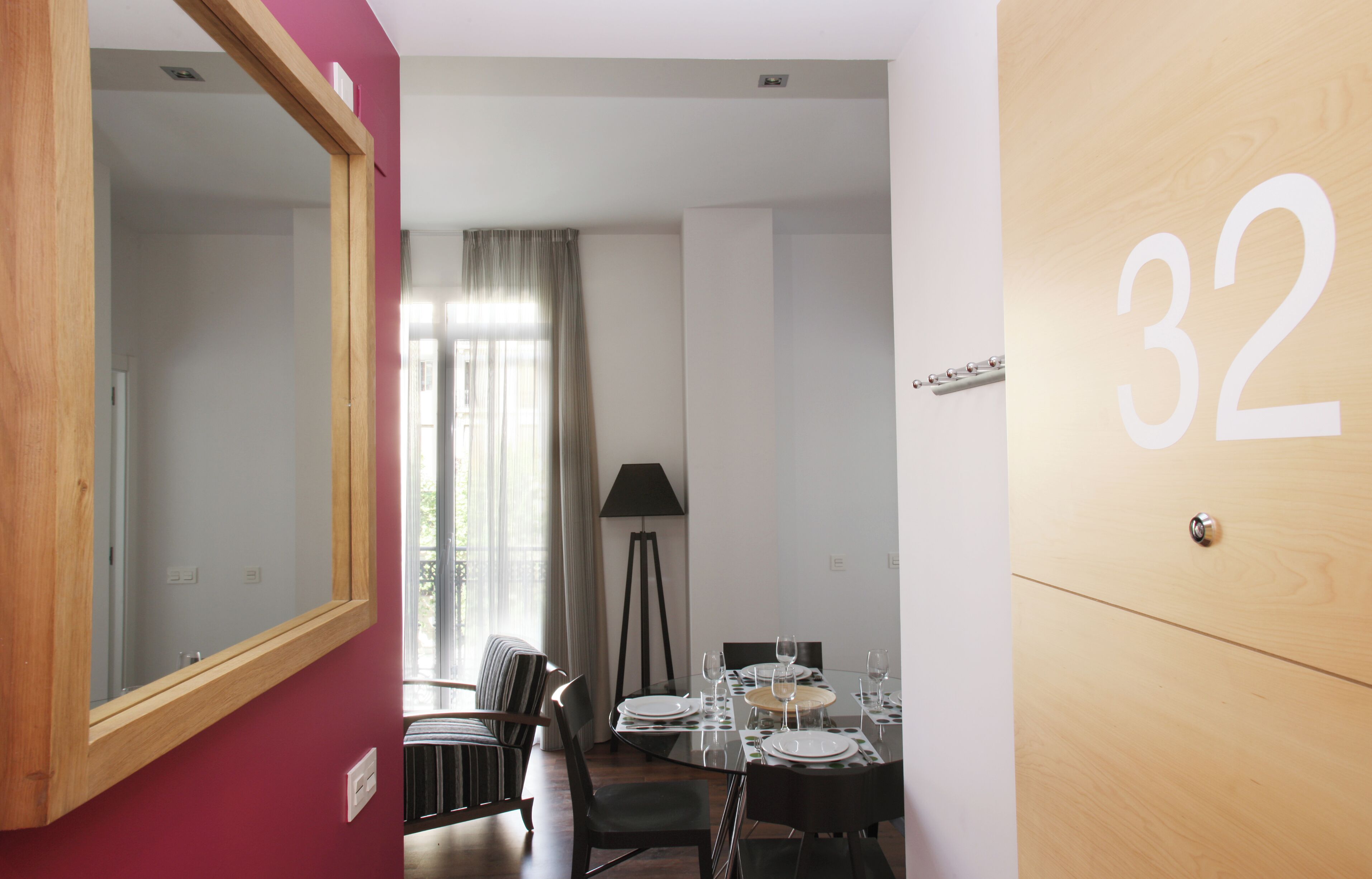 A room with a dining table set for four, a lamp, and a mirror.