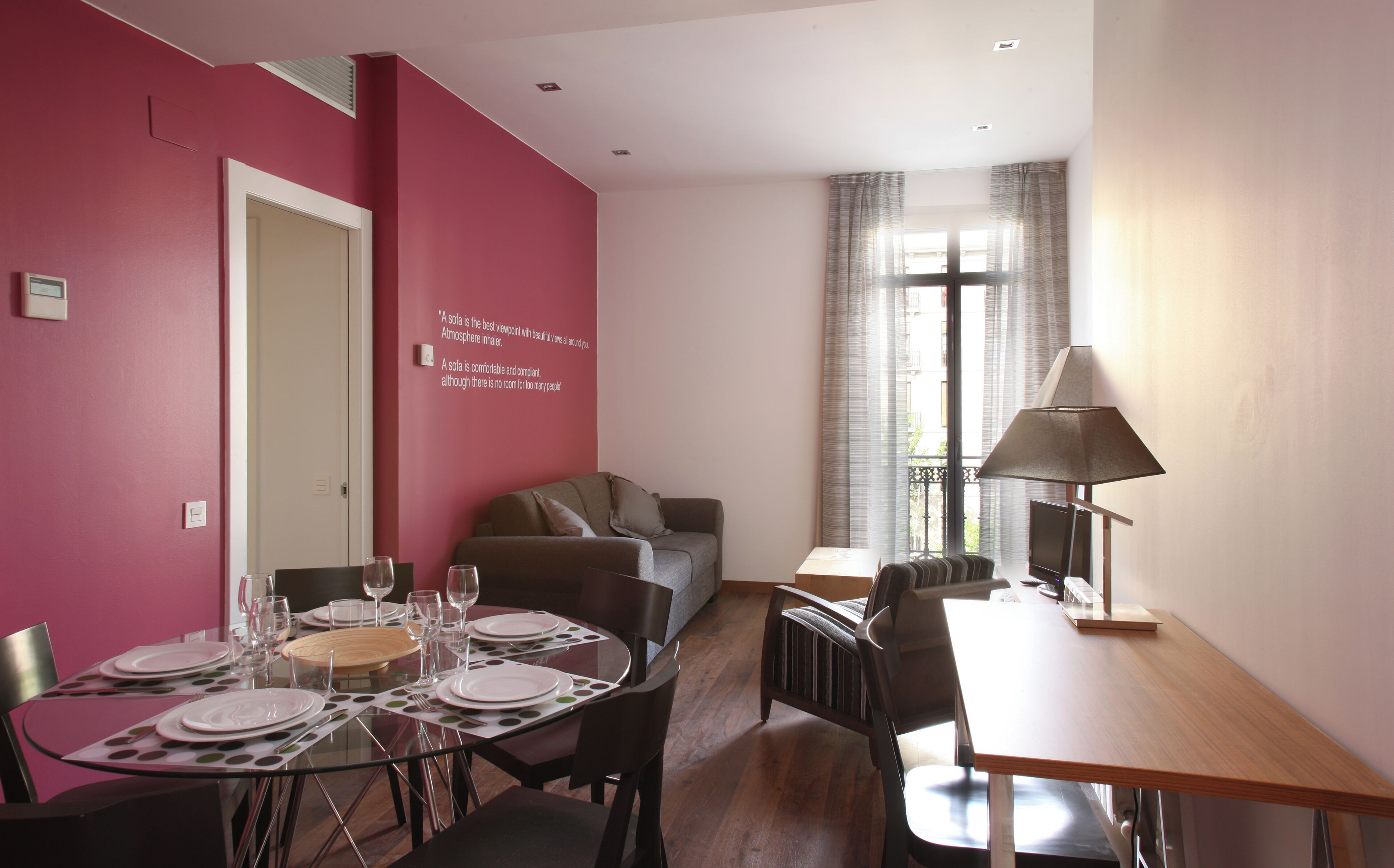 A dining area with a table set for four, a sofa, and a lamp.