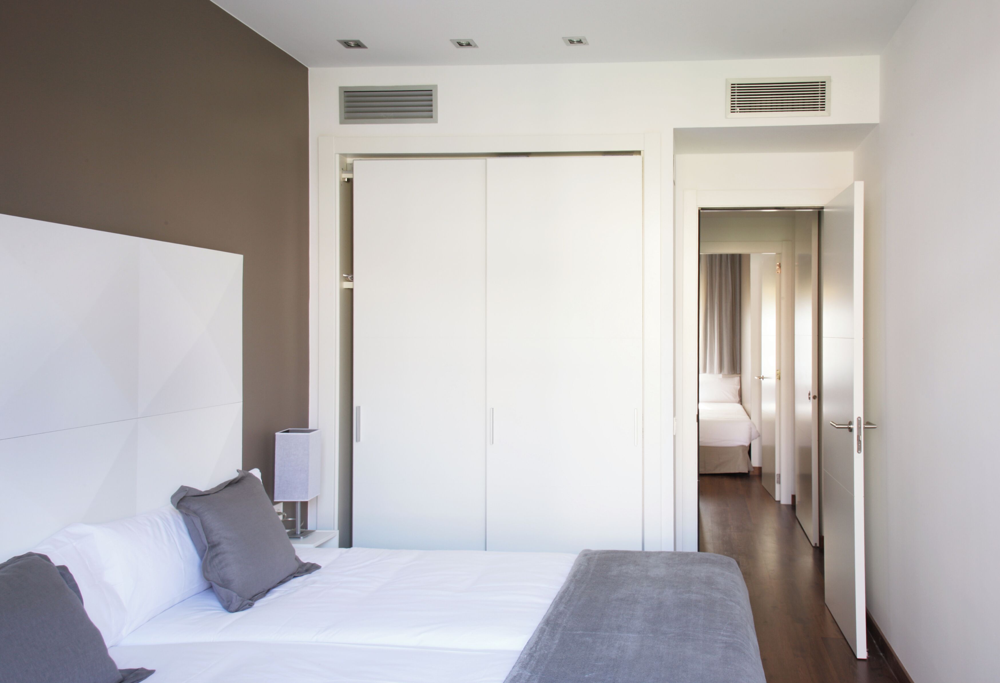 A modern hotel room with a large bed, a wardrobe, and a walk-in closet.
