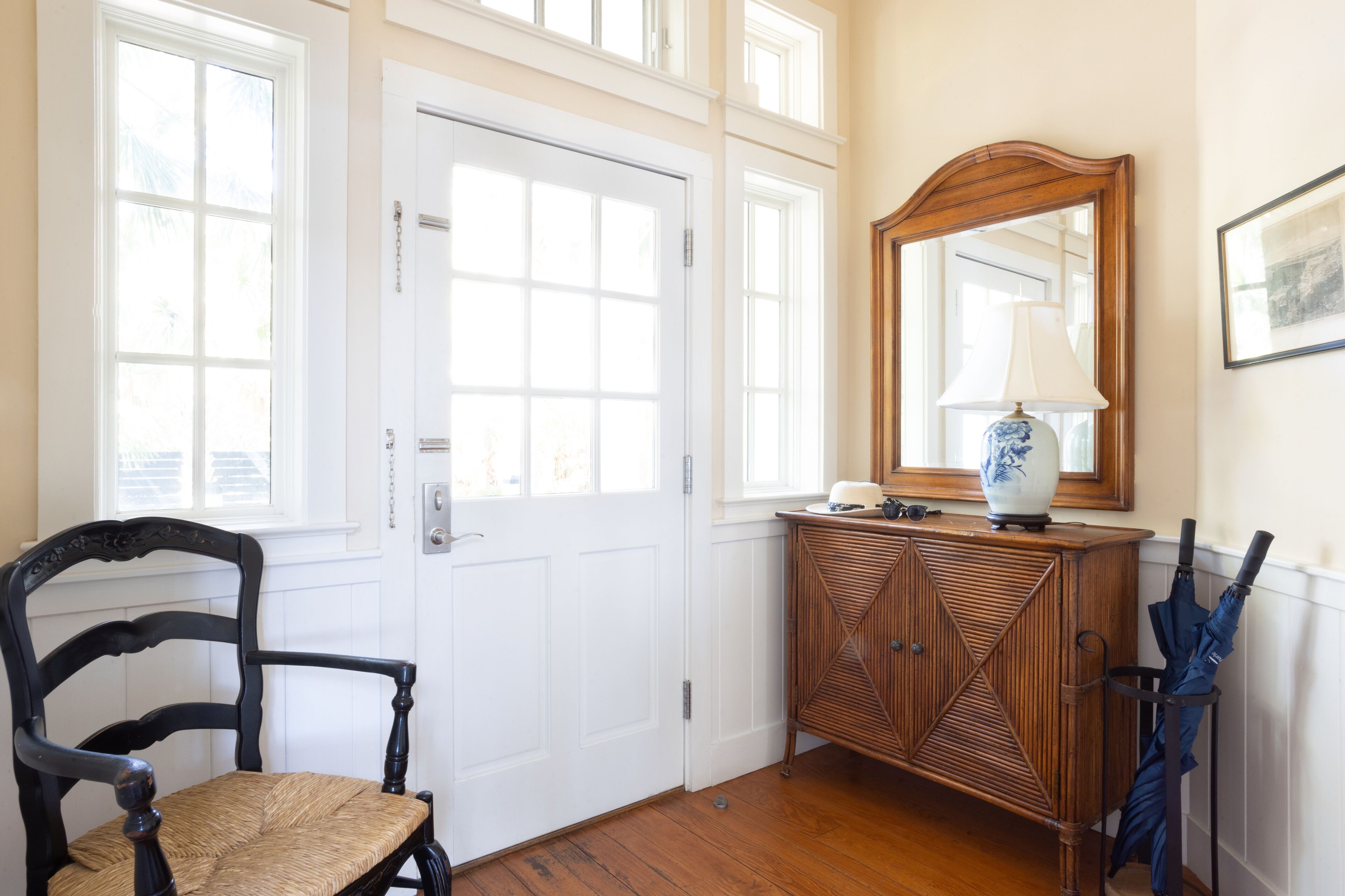 A room with a wooden chair, a white door, a wooden cabinet, and a mirror.
