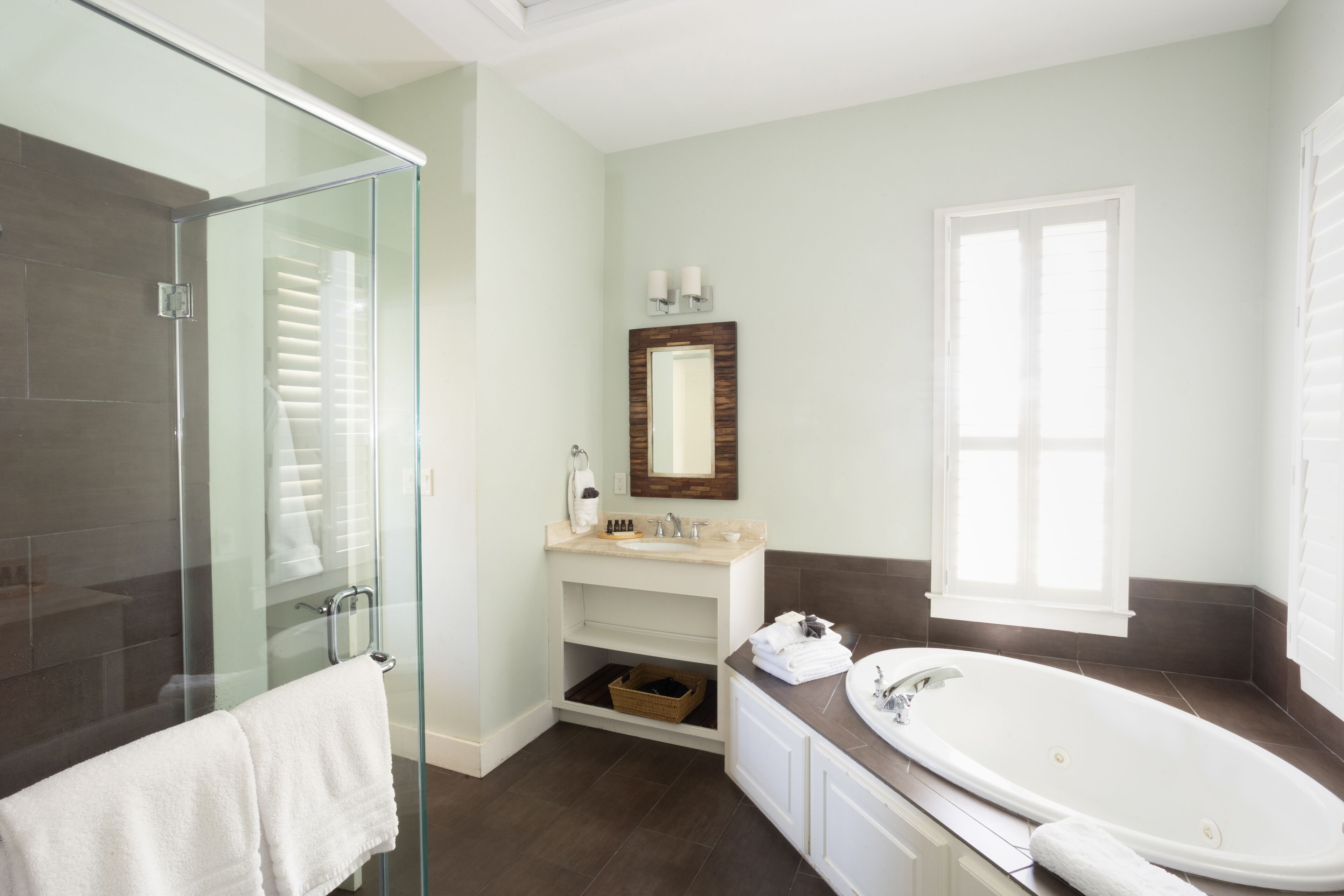 Un baño moderno con cabina de ducha de vidrio, una bañera independiente y un mueble lavamanos con espejo.
