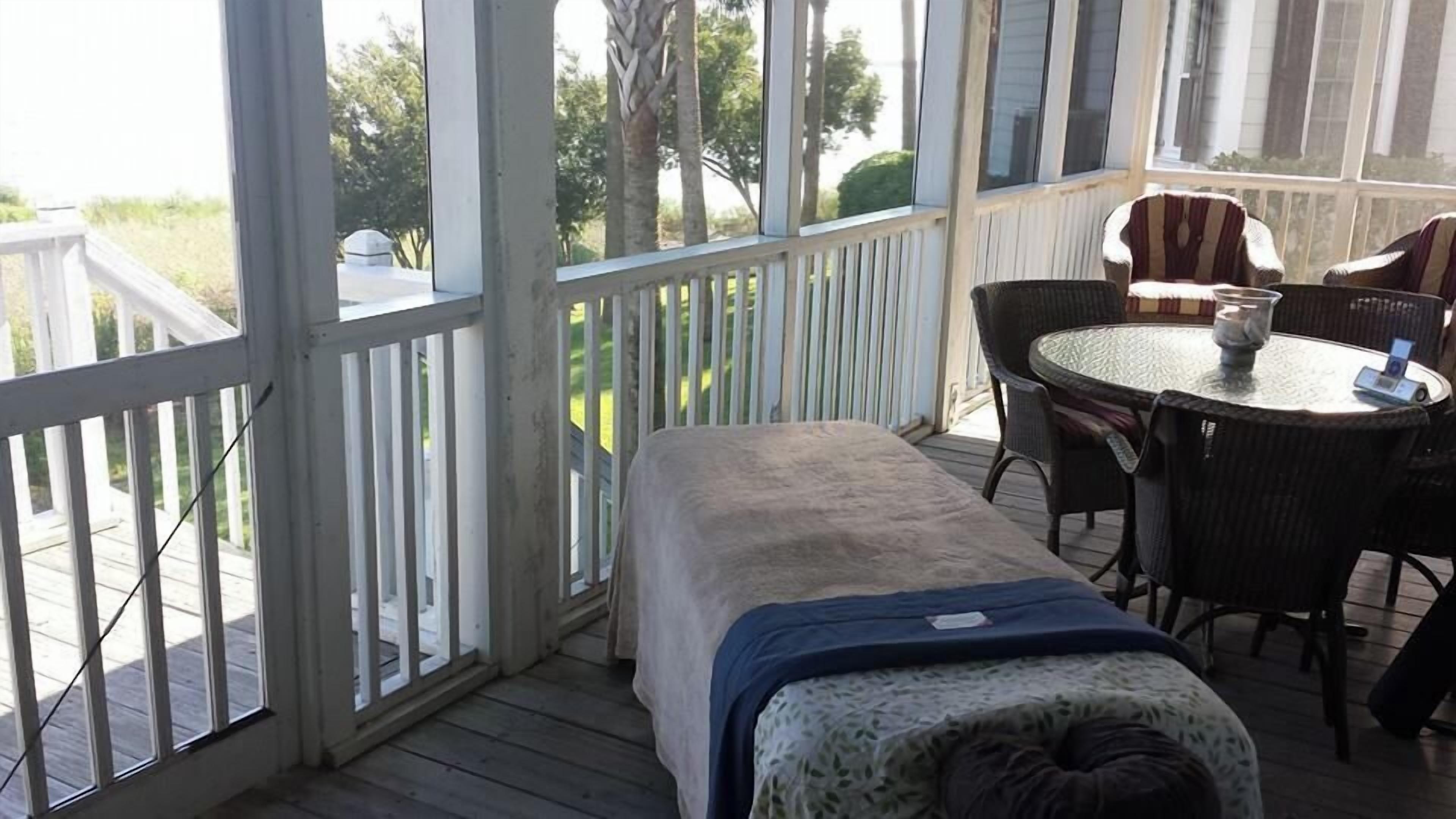 A covered outdoor area with a bed, a table, and chairs.