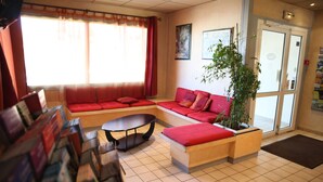Un lobby moderno con un sofá rojo, una mesa de centro y una planta en maceta.
