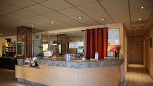 Zona de recepción de un hotel con mostrador de mármol, un reloj y un mapa en la pared.