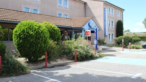 Un hotel con un cartel de contacto, una antena parabólica y un estacionamiento.