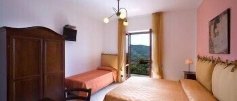 Une chambre à coucher avec un lit, un bureau et une armoire. Il y a une fenêtre donnant sur l’extérieur.