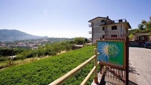 A building with a balcony overlooking a green landscape and mountains in the distance. - Casa Pendola (Agerola)