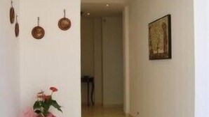 A hallway with a vase of flowers, a wall-mounted picture, and a door at the end. - Casa Pendola (Agerola)