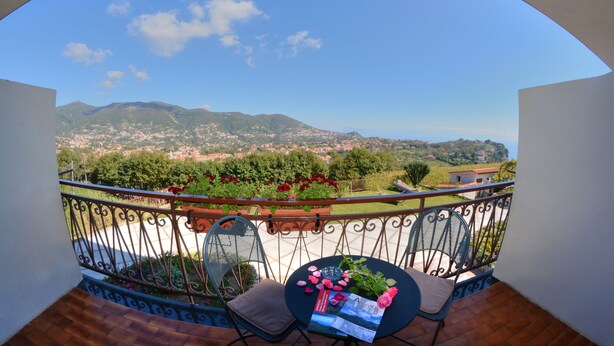 A balcony with a view of a mountainous landscape, a table with a magazine, and two chairs. - Casa Pendola (Agerola)