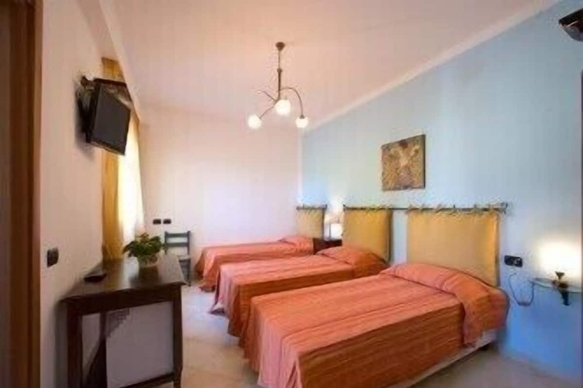 A hotel room with two beds, a desk, a chair, a television, and a ceiling light.