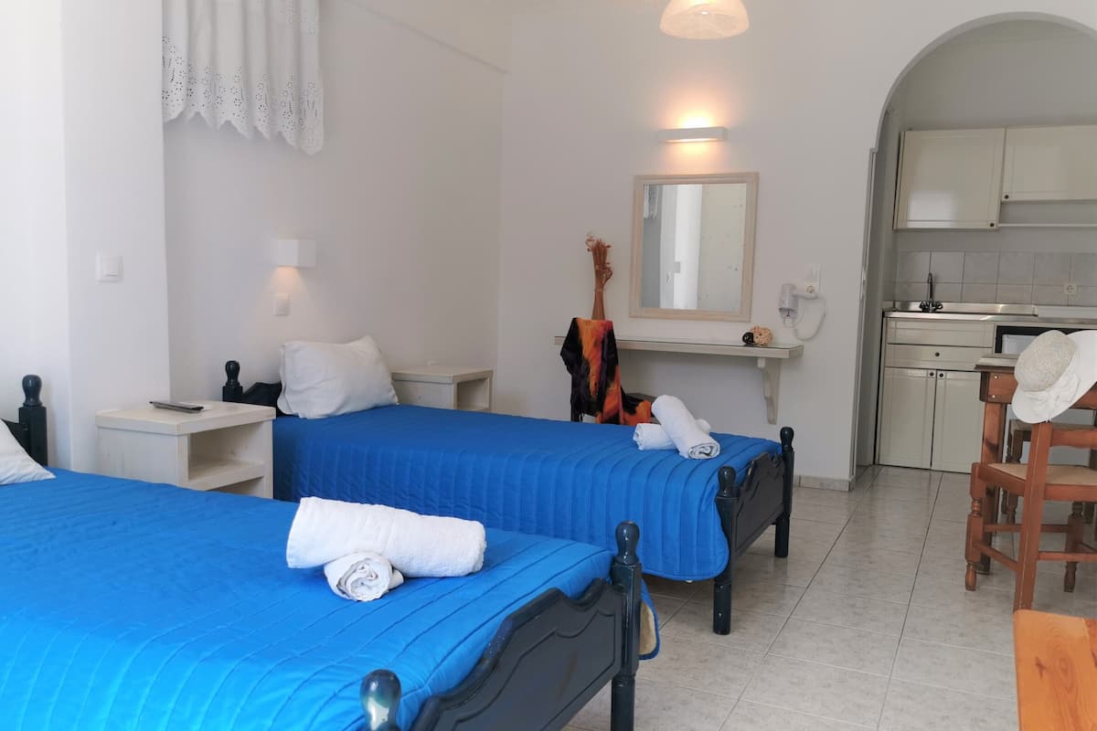 A hotel room with two beds, a small kitchenette, and a bathroom.