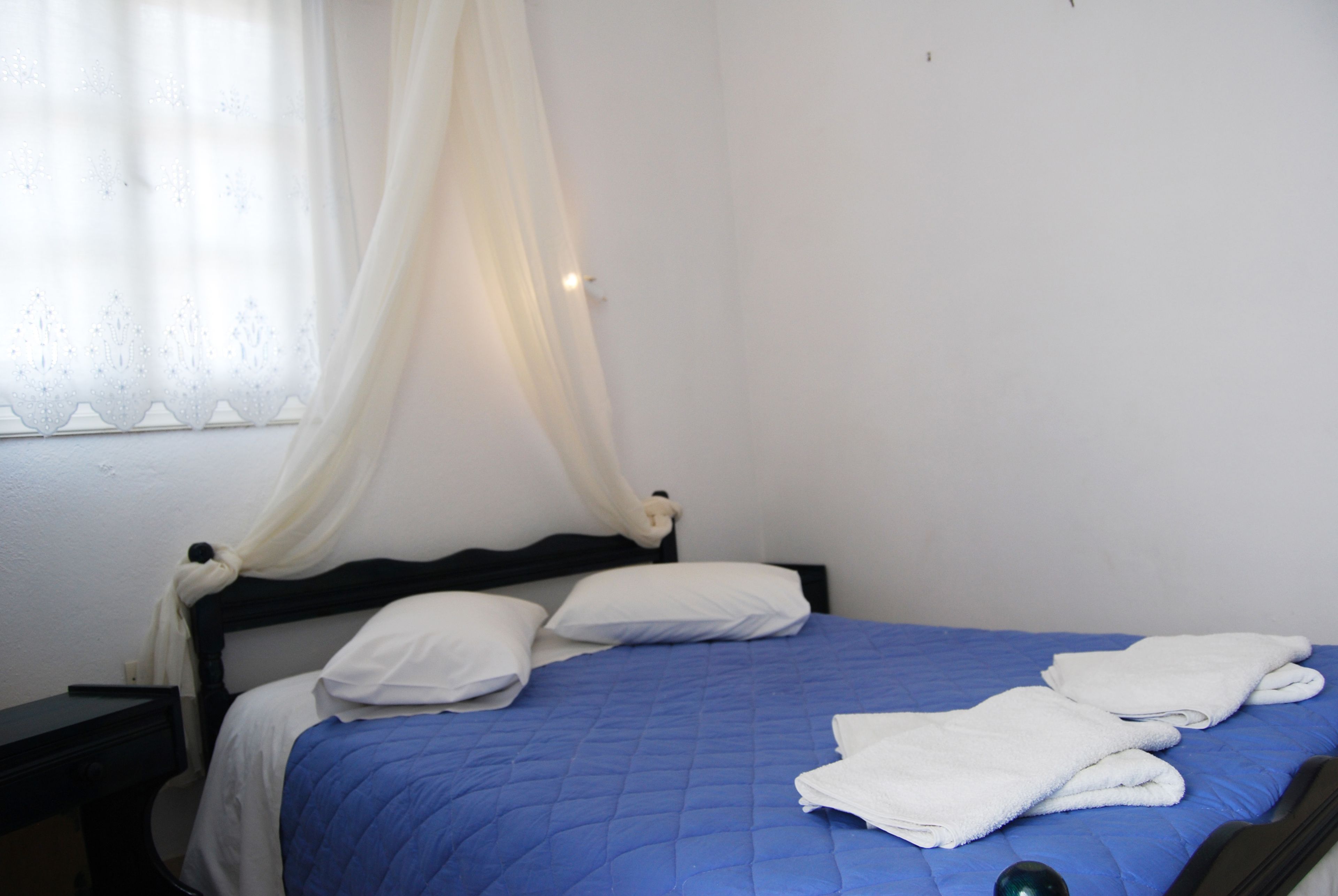 A bed with a blue quilt, white pillows, and a white canopy.