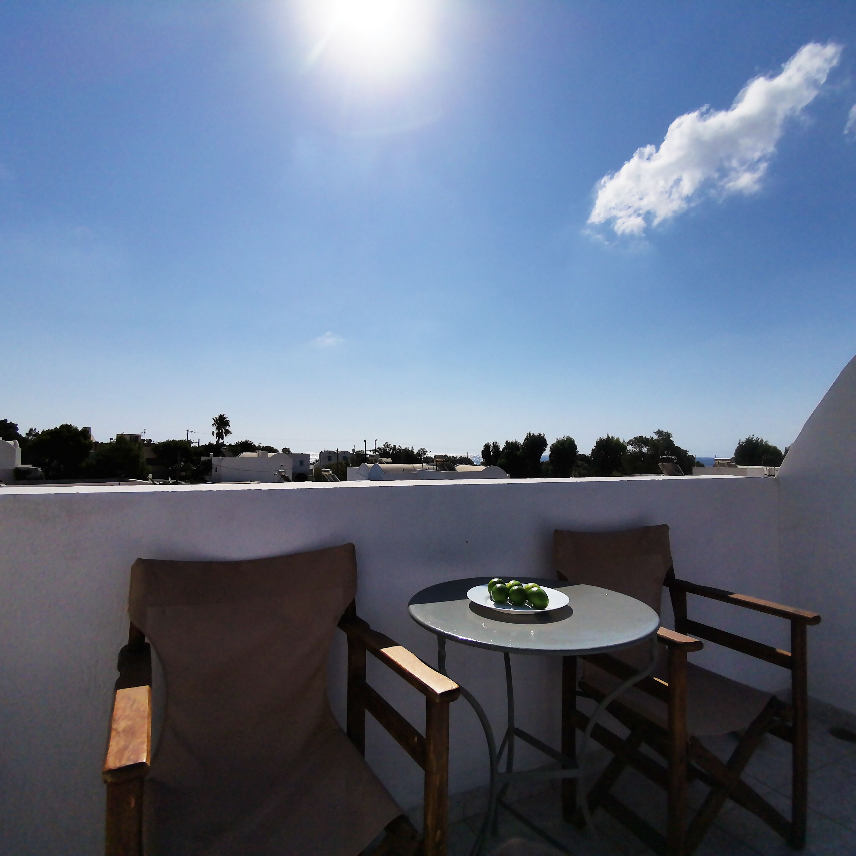 A balcony with a table and chairs, overlooking a cityscape.