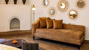 A room with a brown sofa, patterned bedspread, and decorative mirrors on the wall.