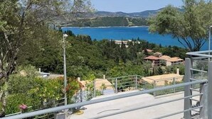 A concrete staircase leading to a balcony overlooking a coastal area with trees and buildings. - Thealos Village (Lefkada)