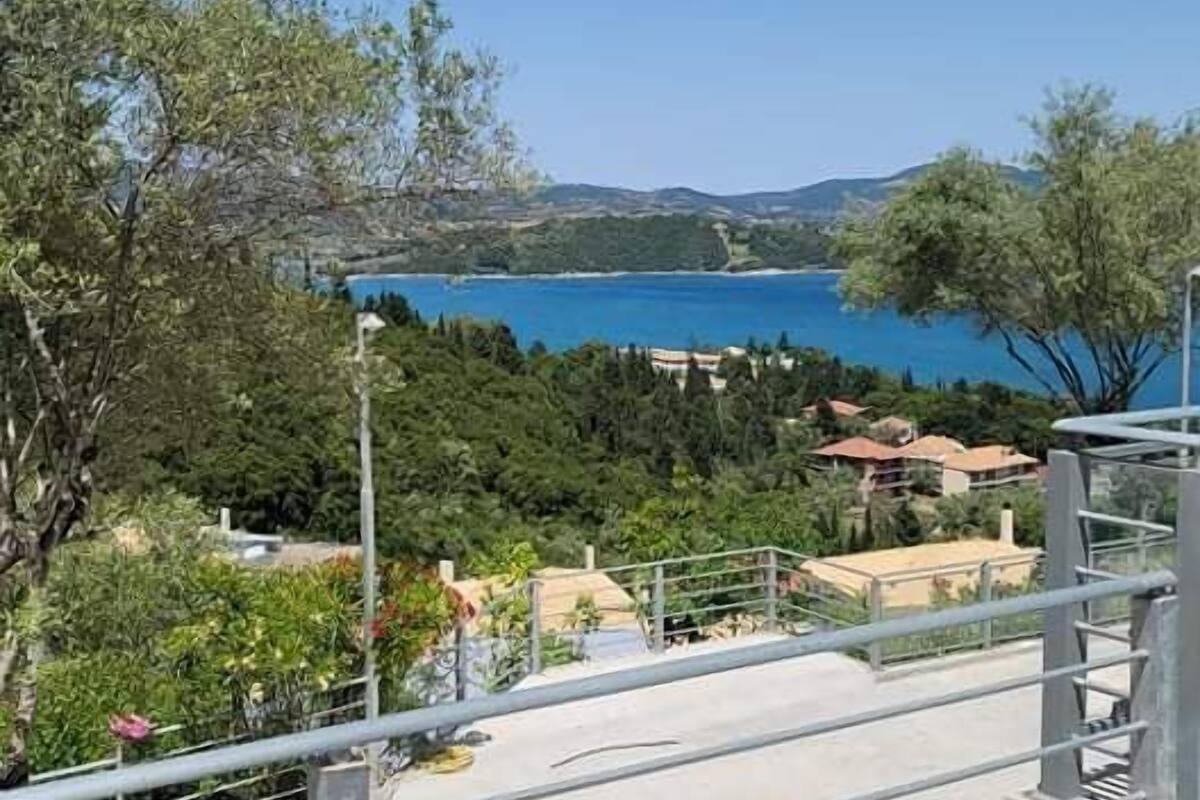 A concrete staircase leading to a balcony overlooking a coastal area with trees and buildings.