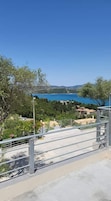 Una escalera de hormigón que lleva a un balcón con vistas a una zona costera con árboles y edificios.