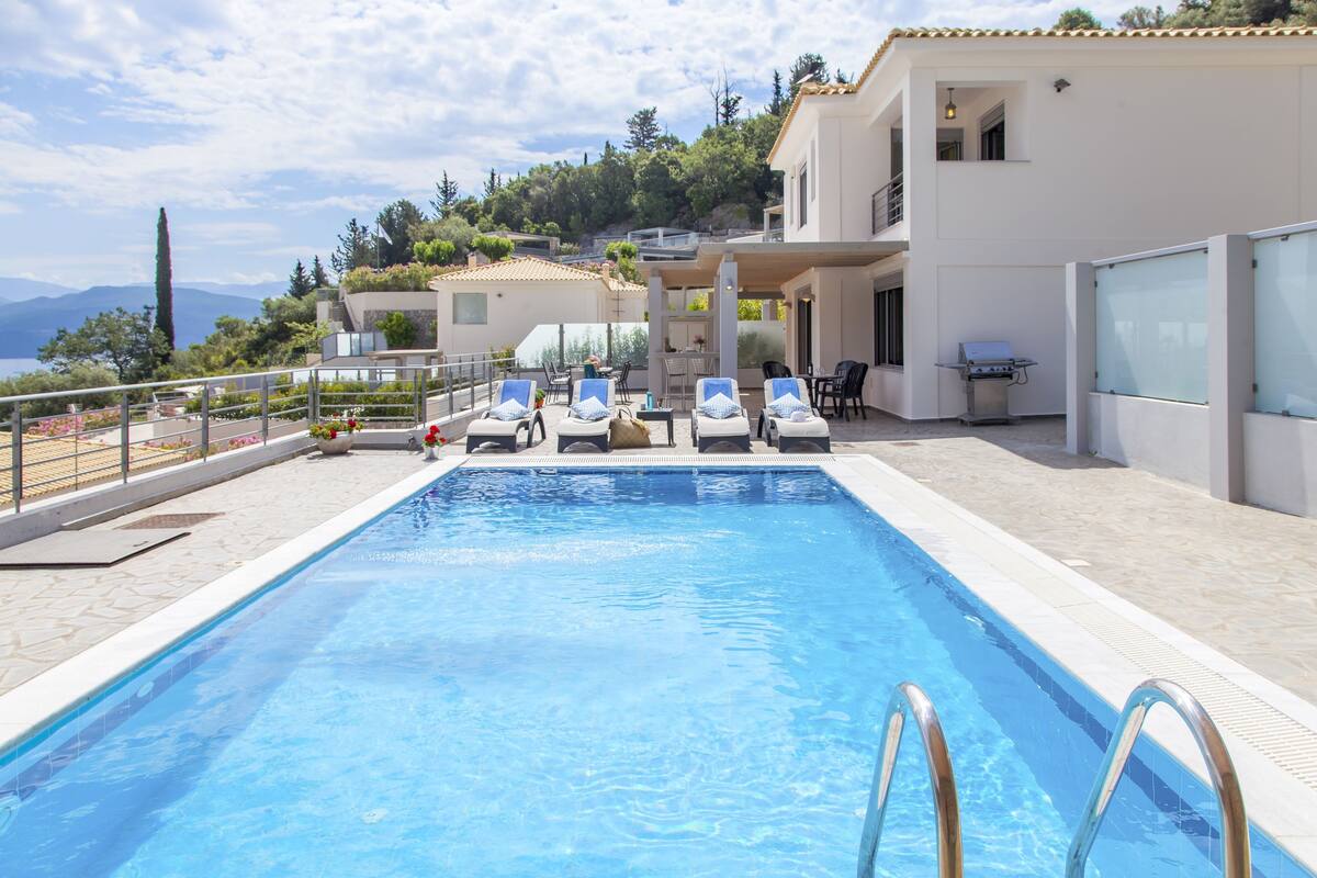A swimming pool with lounge chairs, a barbecue area, and a view of a hillside.