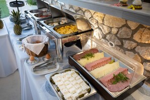 A buffet with various food items including eggs, sausages, and cheese. - Thealos Village (Lefkada)