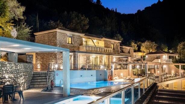 A luxurious pool area with a stone wall, a hot tub, and a dining area with outdoor seating. - Thealos Village (Lefkada)
