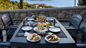 A table set for breakfast with a scenic view of a lake and mountains. - Thealos Village (Lefkada)