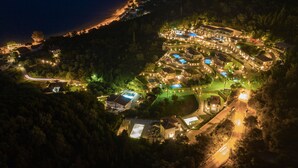 An aerial view of a resort with multiple buildings, swimming pools, and well-lit pathways. - Thealos Village (Lefkada)