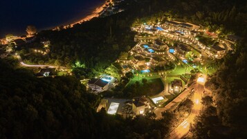 Vista aérea de un complejo turístico con varias edificaciones, piscinas e iluminadas senderas.