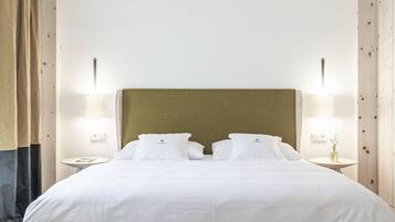Ein ordentlich bezogenes Bett mit weißen Leinentüchern und zwei Kissen, an beiden Seiten mit Nachttischen und Lampen, in einem Zimmer mit Holzvertäfelung und schlichtem, klaren Design.