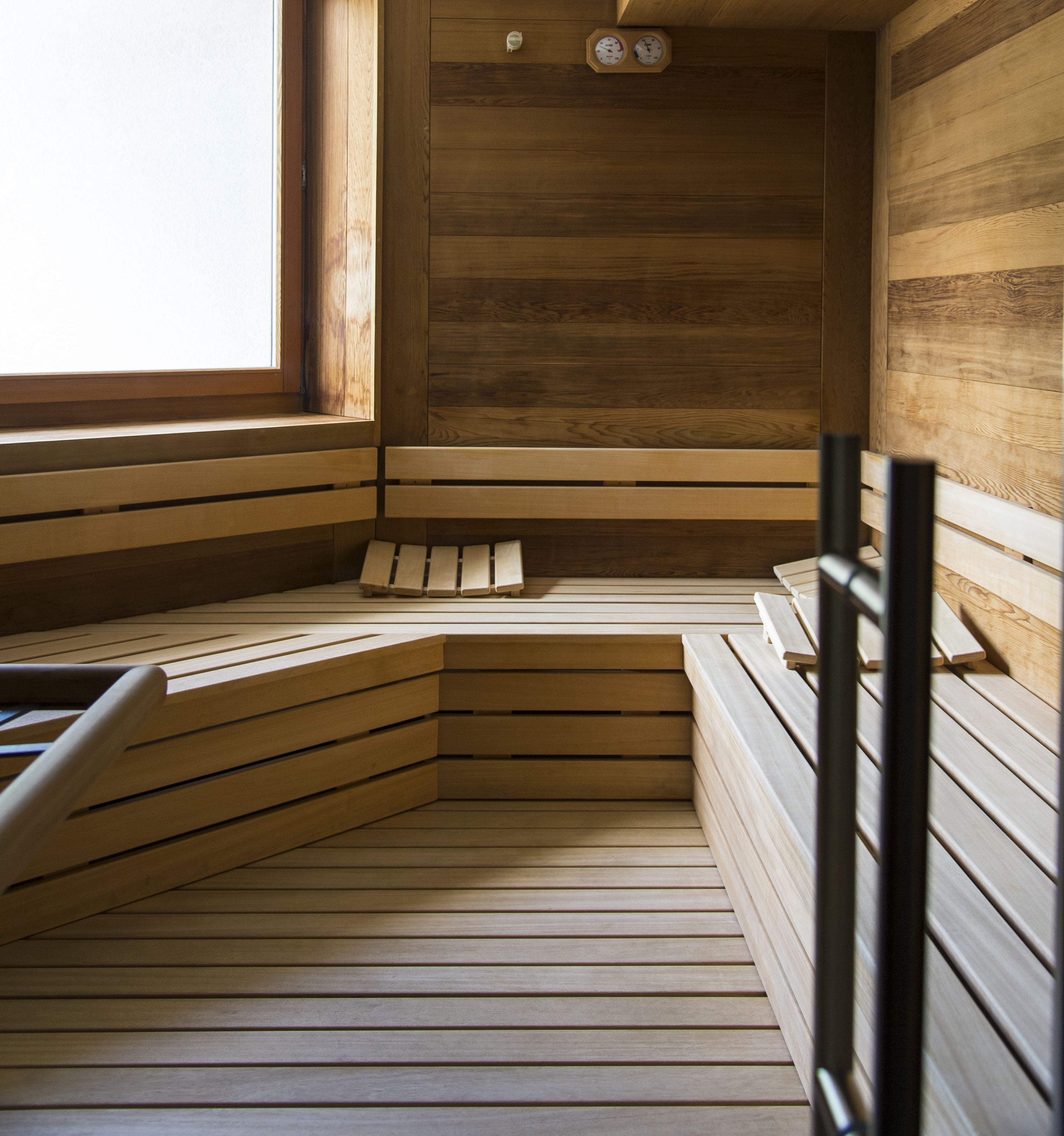 A wooden sauna with benches and a bench in the foreground.