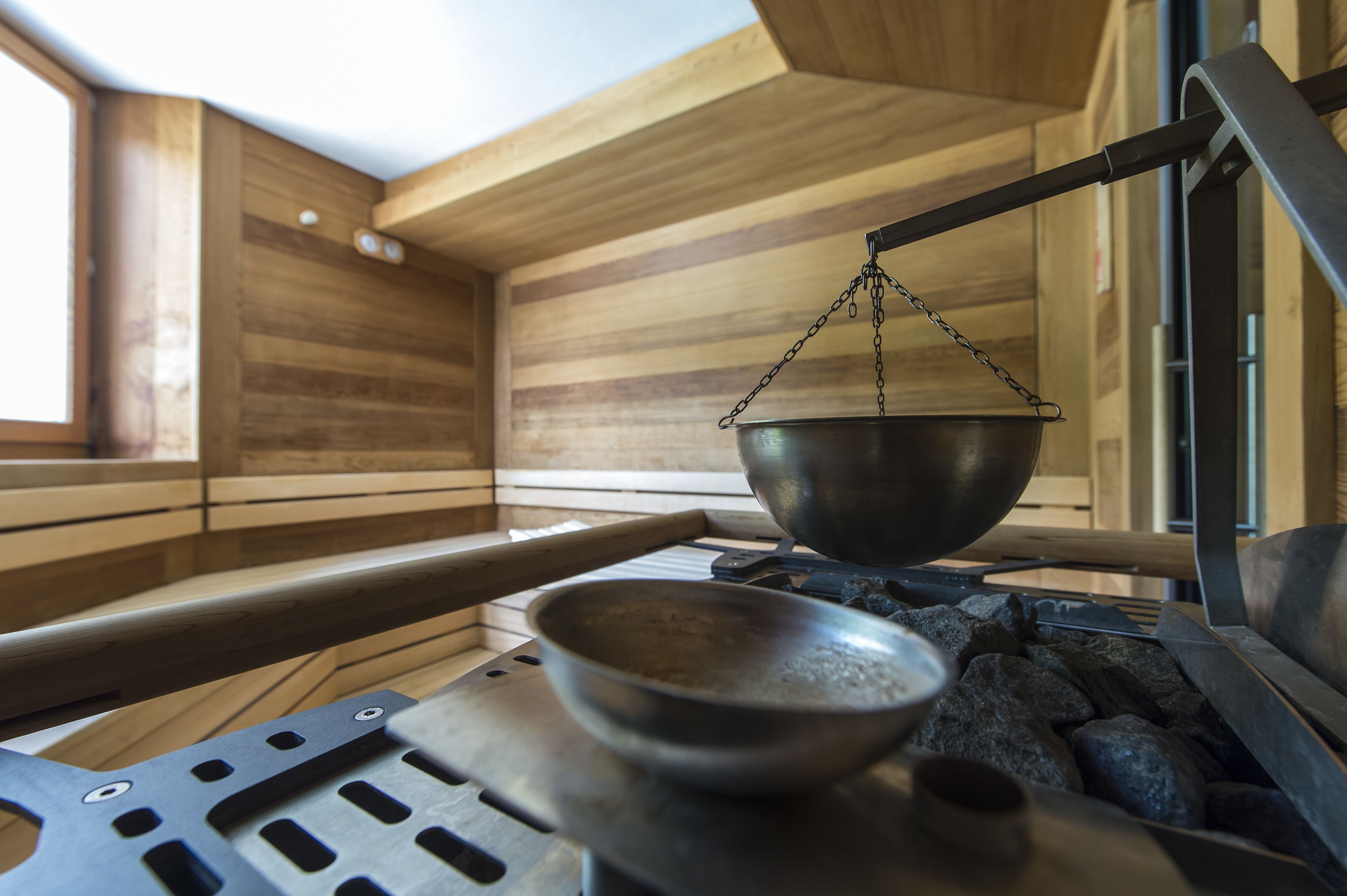 Un sauna con paredes de madera, una gran palangana metálica y un banco.