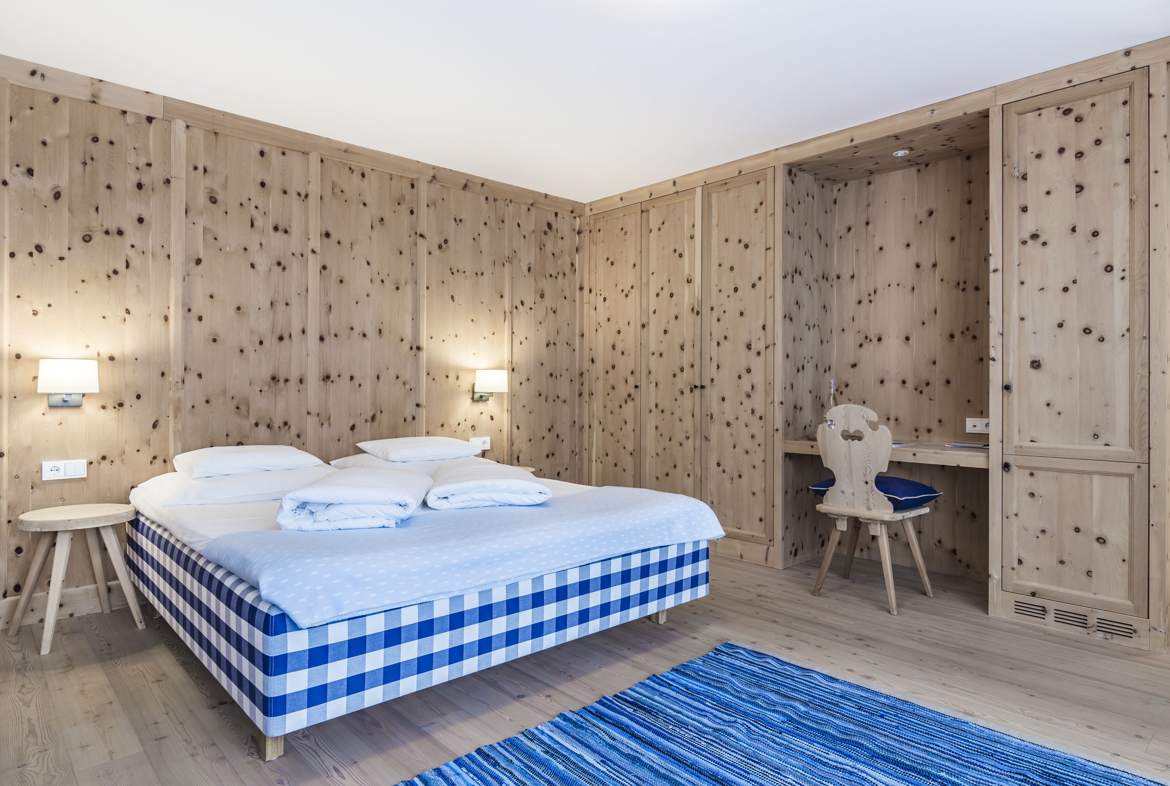 Een kamer met houten lambrisering, een bed, een bureau en een stoel.