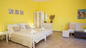 A bedroom with two beds, a wardrobe, a bedside table, a lamp, and a small table with a vase.