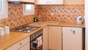 Eine kompakte Küche mit einer Holzausziehtheke, einem Backofen, einer Spüle und einem kleinen Kühlschrank.