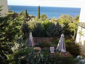 A balcony with a view of the sea, surrounded by greenery and two covered seating areas. - Argo Studios (Chios)