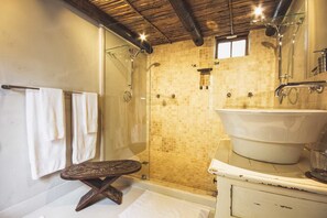 Une salle de bain dotée d’une douche à parois de verre, d’une grande baignoire sur pieds et d’un banc en bois.