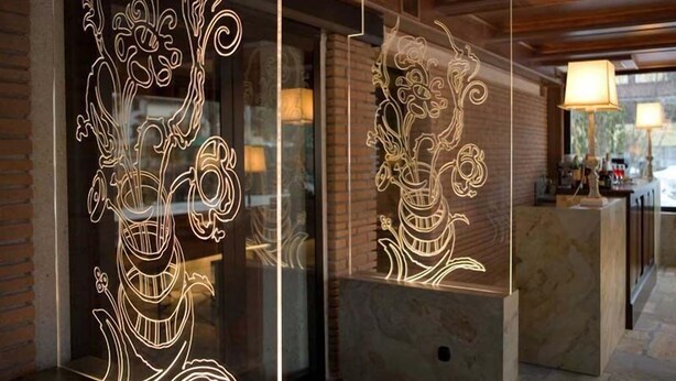 A reception area with a marble counter and a glass partition featuring illuminated floral designs. - Hotel Sport Daniel (Pescasseroli)
