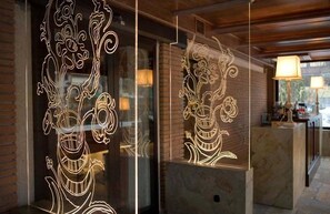 Un área de recepción con mostrador de mármol y separador de vidrio con diseños florales iluminados.