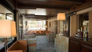 A bar area with seating and a counter, featuring a stone floor and brick walls. - Hotel Sport Daniel (Pescasseroli)