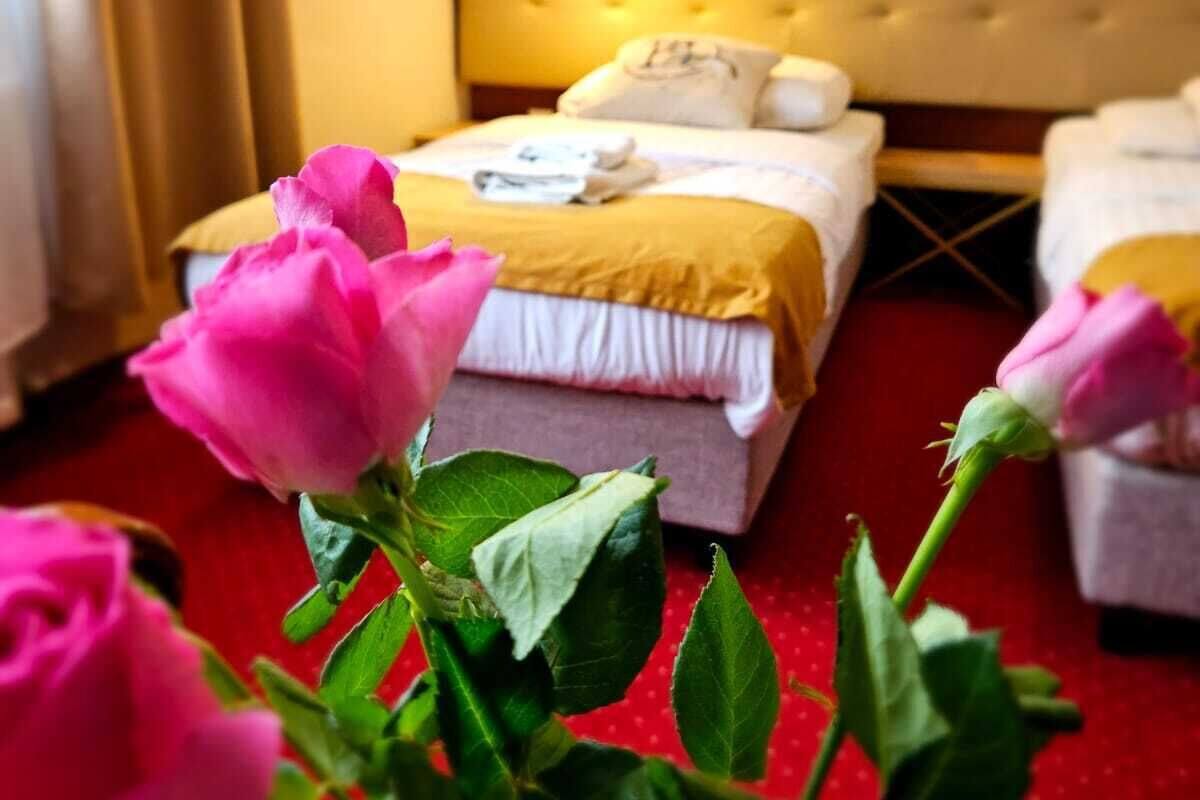 A hotel room with a bed, a bedside table, and a window with curtains.